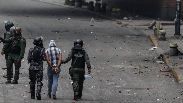 Elementos de la Policía Nacional Bolivariana detienen a un manifestante en Caracas.