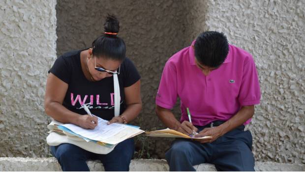 Dos jóvenes llenan solicitudes de empleo en la ciudad de Cancún.