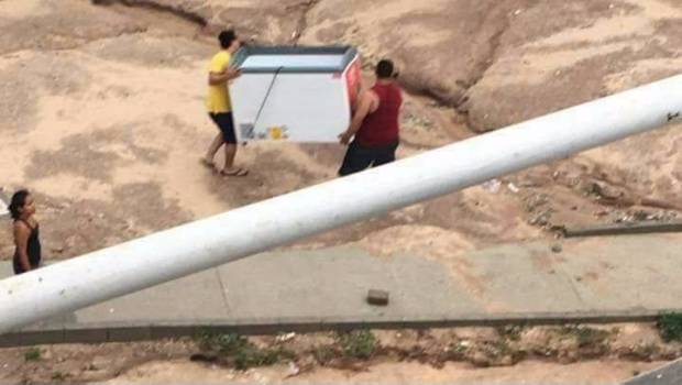 Estos hombres llevan un refrigerador de conocida empresa de helados. 