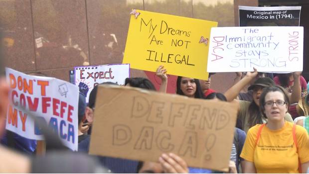 Jóvenes inmigrantes y simpatizantes caminan sosteniendo carteles durante una manifestación en apoyo de Acción Diferida por Llegadas de Niñez (DACA) en Los Ángeles, California.