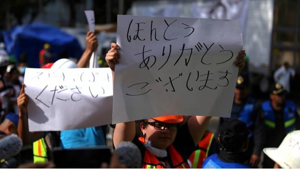 Una mujer sostiene un letrero con un mensaje de agradecimiento al equipo de rescatistas japoneses que laboran en CDMX.