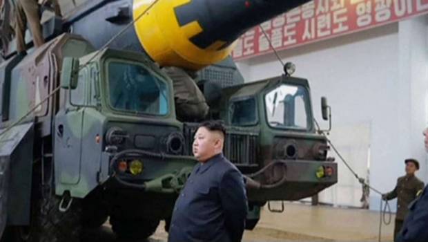 El líder de Corea del Norte, Kim Jong-un, posando a lado de un misil balístico. 