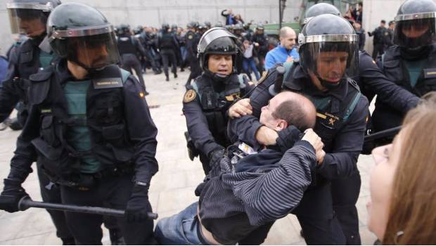 Elementos de la Guardia Civil de España arrastran a un hombre de una casilla de votación.