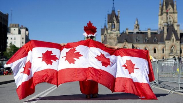 Canadá Un hombre camina envuelto por banderas de su país en Ottawa, la capital de Canadá.